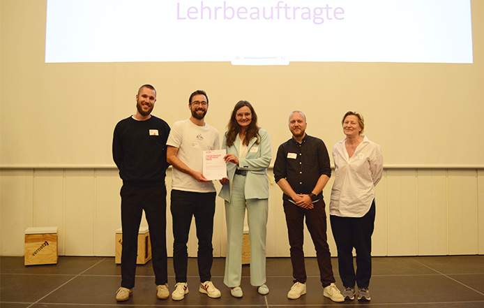 Fünf Personen auf einem Podium bei der HFT-Lehrpreisverleihung mit Urkundenübergabe