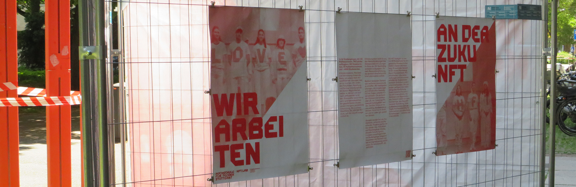Drei Plakate an Bauzaun mit Aufschrift Wir arbeiten an der Zukunft
