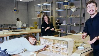 Drei Studierende bauen an einem Architektur-Modell