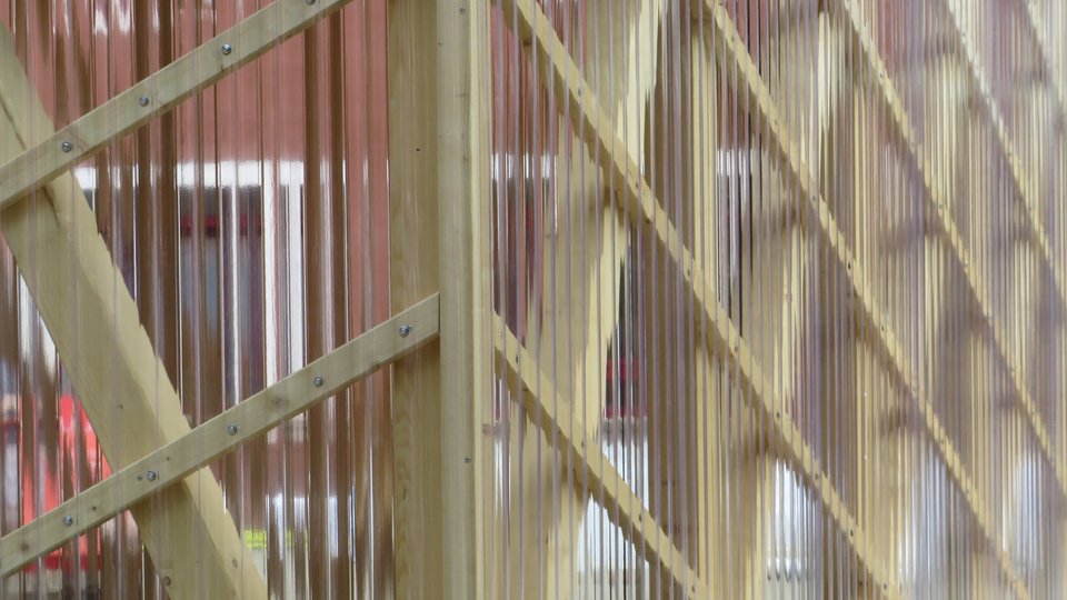 Außenansicht eines Pavillons mit Stützen und Diagonalstreben aus Holz sowie durchsichtiger Plexiglas-Fassade