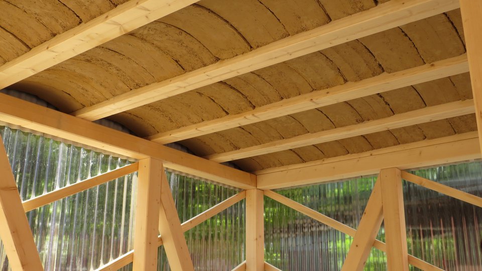 zu sehen ist das Rauminnere mit Stützen, Träger und Diagonalstreben aus Holz sowie einer gewölbten Decke aus Lehmziegeln
