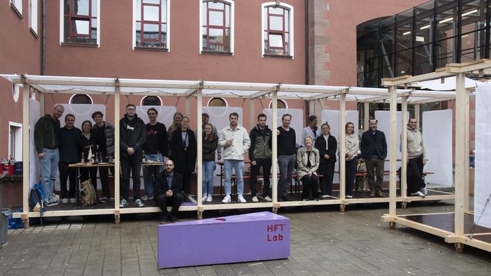 Gruppe Studierender im selbst gebauten Holz-Pavillon