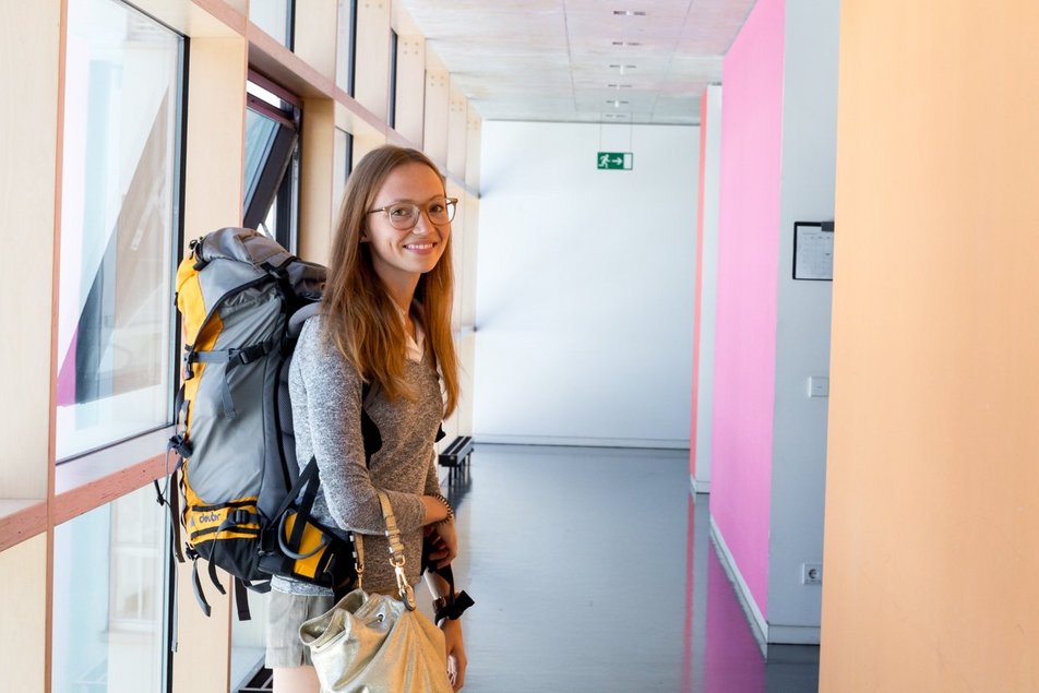 Eine Studentin mit Rucksack steht im Flur