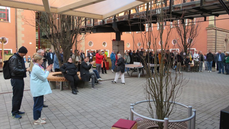 Blick aus Mehrzweckraum in Innenhof mit Gruppe Personen