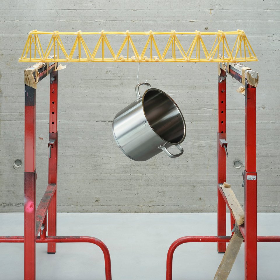 Darstellung einer Brücke aus Spaghetti, an der ein Topf hängt