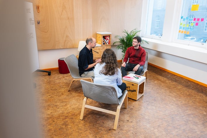 Drei Personen sitze zusammen und unterhalten sich