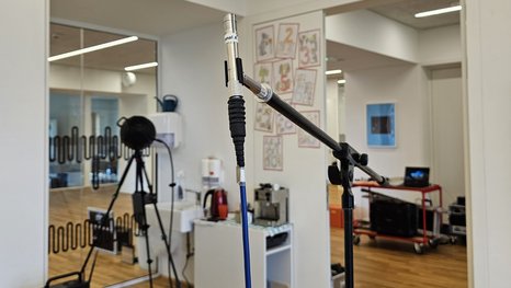 Akustik-Messsituation in einem Klassenzimmer mit dem Lautsprecher im Hintergrund und dem Messmikrofon im Vordergrund