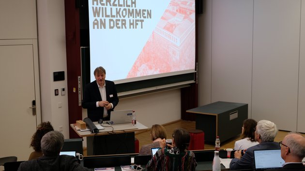 Der Referen stellt eine Folie vor "Willkommen an der HFT"