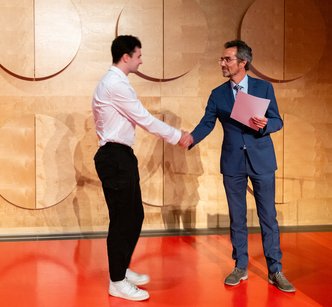 Preisübergabe von Bernd Göhner an einen Studierenden auf der Graduierungsfeier 2024