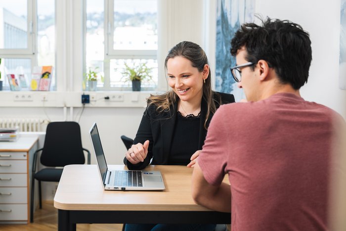 Zwei Mitarbeitende im Gespräch an Besprechungstisch
