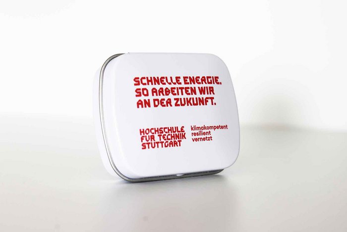Weiße Bonbondose mit roter Aufschrift "Wir freuen uns auf dich - deine ZSB" und rotem Logo der HFT Stuttgart