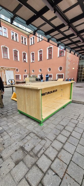 Eine Holzaufbewahrung für Bierbänke steht im Innenhof der HFT Stuttgart