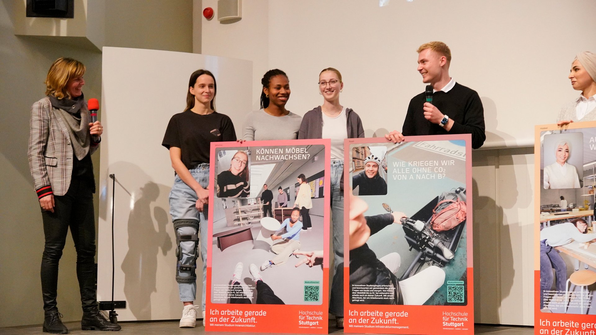 Studierende mit Postern auf einer Bühne