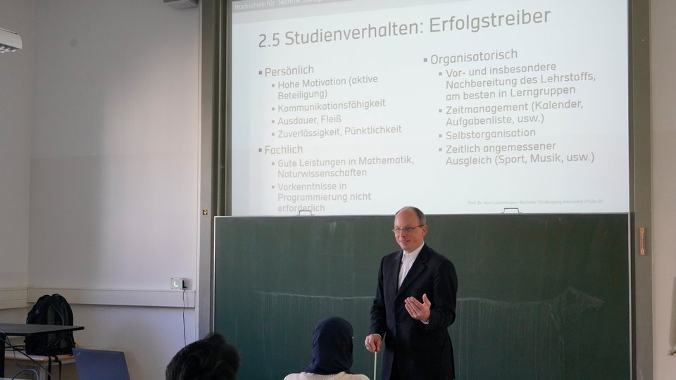 Professor vor einer Tafel mit Informationsmaterial