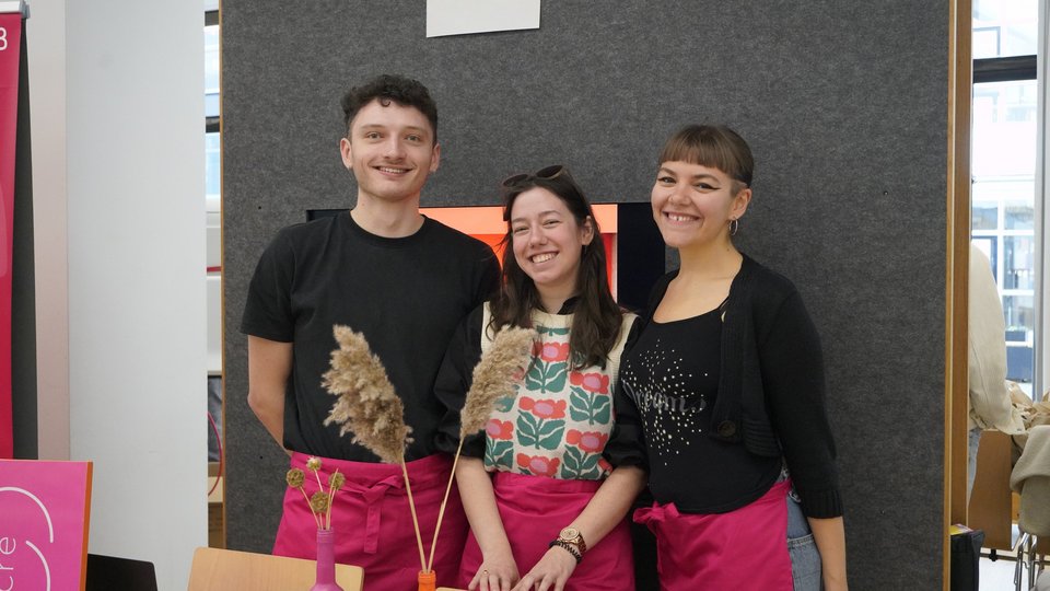 Drei Studierende lachen in die Kamera.