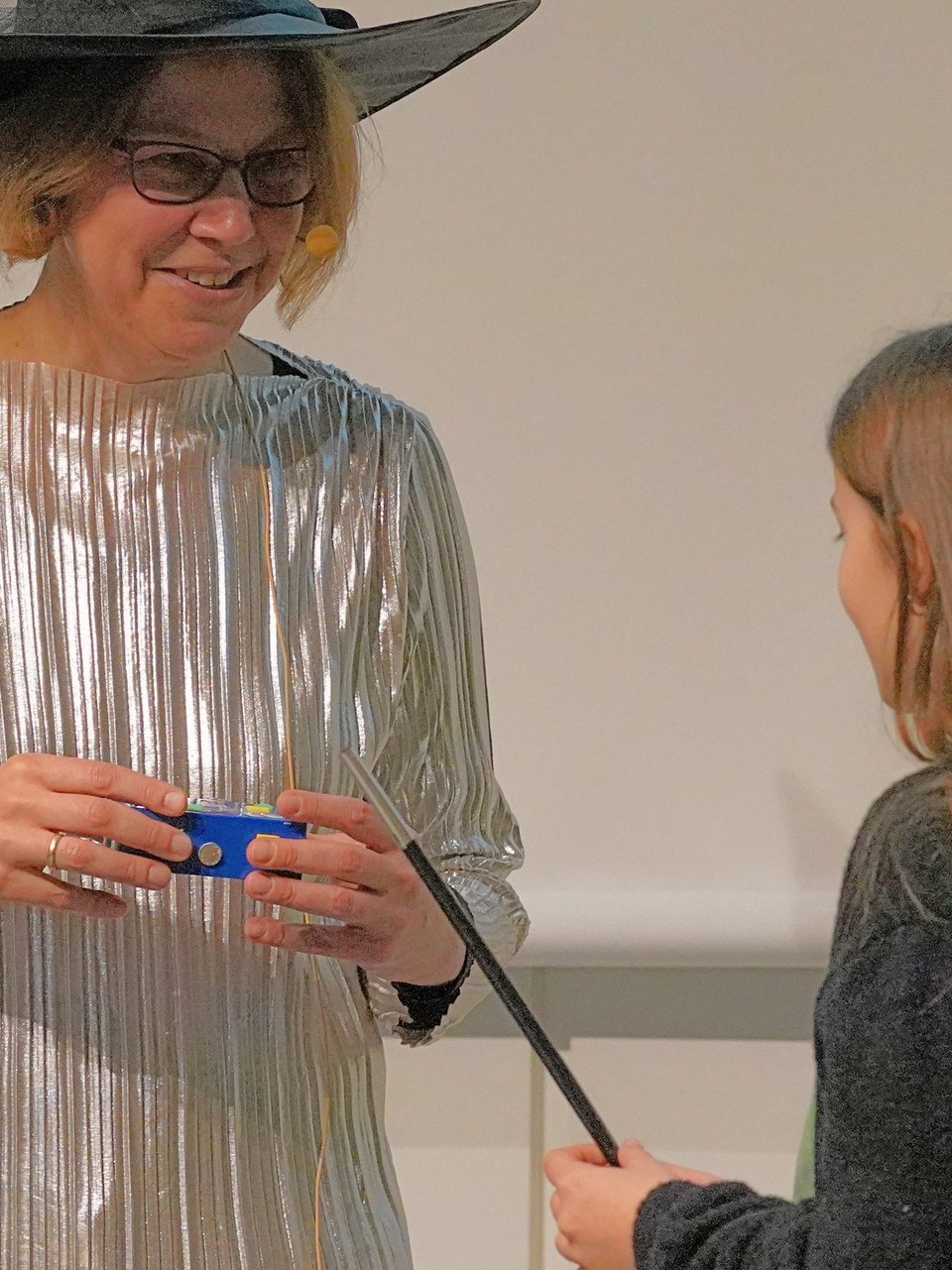 Professorin, als Zauberin verkleidet, mit einem Mädchen auf der Bühne