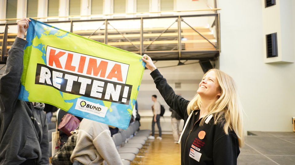 Teilnehmerin hält Banner beim Klimaplanspiel 2025