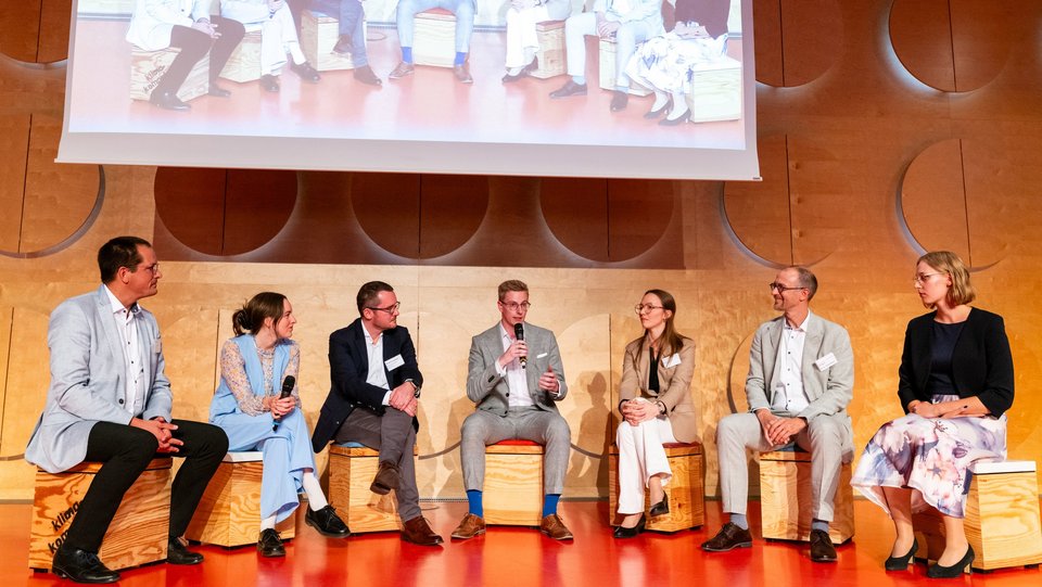 Diskussion sitzender Personen auf der Bühne