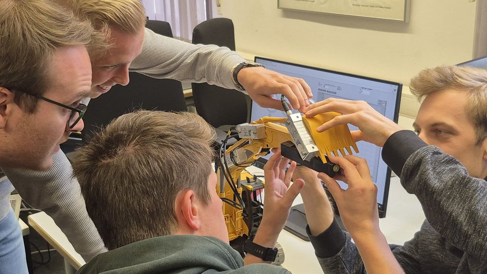 Studenten konfigurieren Mess-Sensoren an einem Bagger-Modell