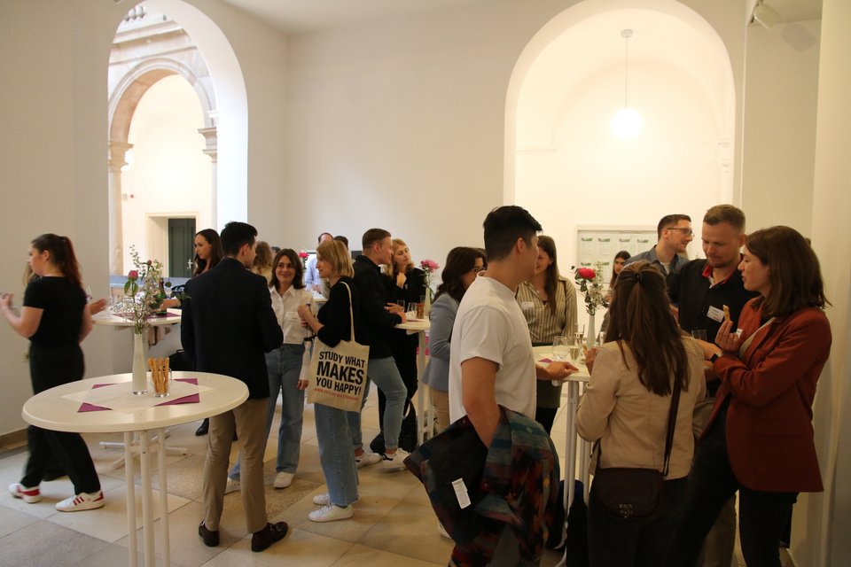 Mehrere Menschen stehen an Stehtischen. 