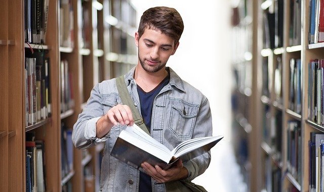 Ein Student, der in einer Bibliothek ein Buch blättert.