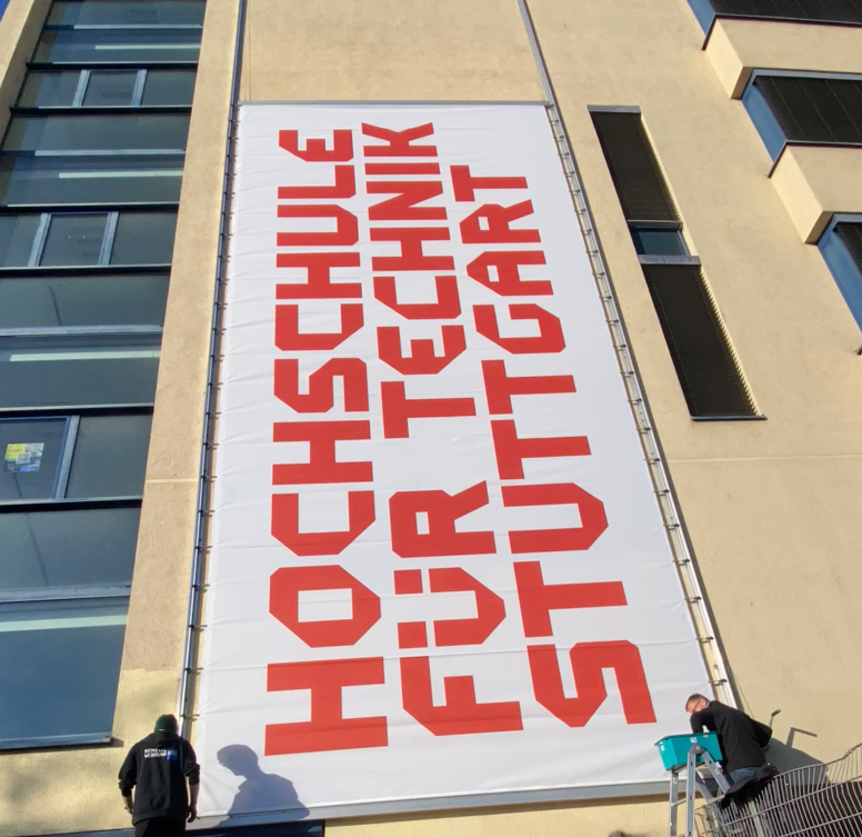 HFT Banner wird an die Fassade des neuen Gebäudes der SBS angebracht